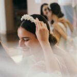 Bride with bridesmaids adjusting headband and preparing for wedding ceremony.